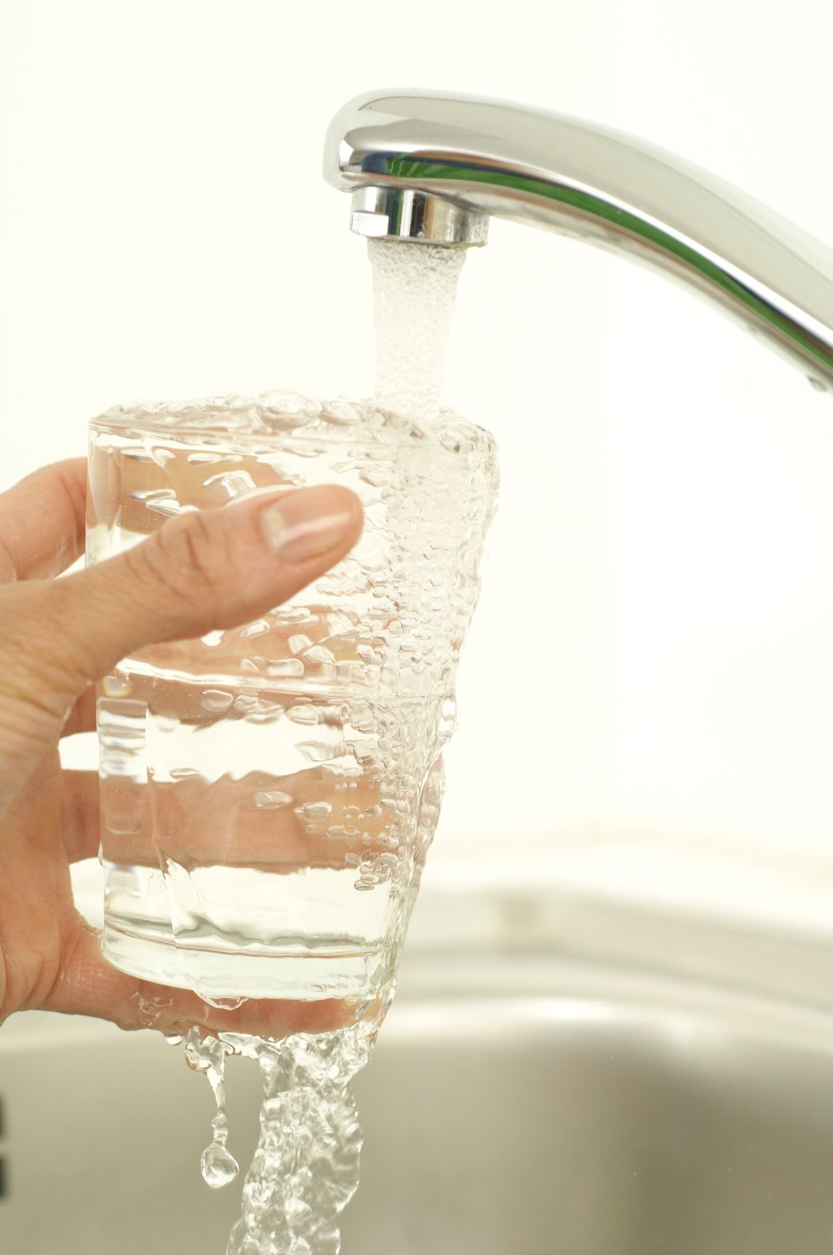 A glass being filled from a kitchen tap, illustrative stock photograph